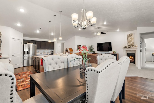 2701 N Ice Fire Pl, Star, ID 83669 - dining space featuring ceiling fan, a chandelier, dark wood-type flooring, vaulted ceiling, and a fireplace