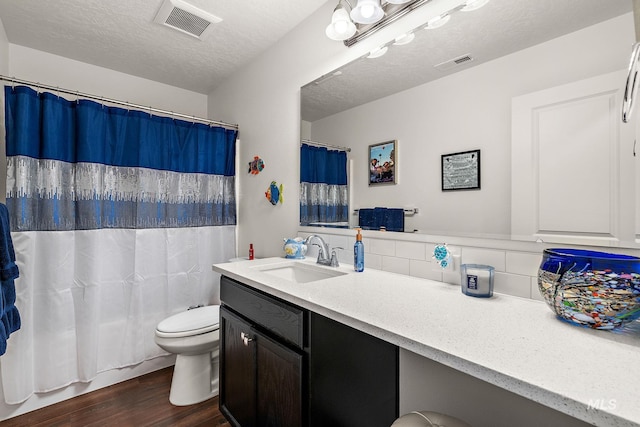 2701 N Ice Fire Pl, Star, ID 83669 - bathroom with toilet, wood finished floors, vanity, a textured ceiling, and tasteful backsplash