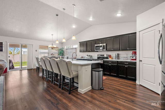 2701 N Ice Fire Pl, Star, ID 83669 - kitchen featuring appliances with stainless steel finishes, a sink, a textured ceiling, a breakfast bar, and lofted ceiling