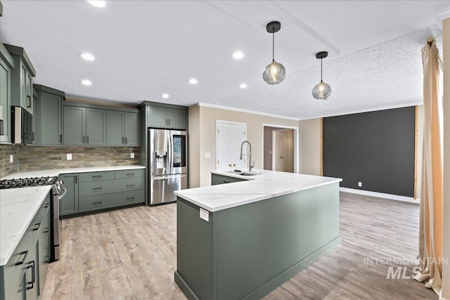 905 S Canyon St, Nampa, ID 83686 - kitchen featuring stainless steel appliances, backsplash, an island with sink, a sink, and light wood-style flooring
