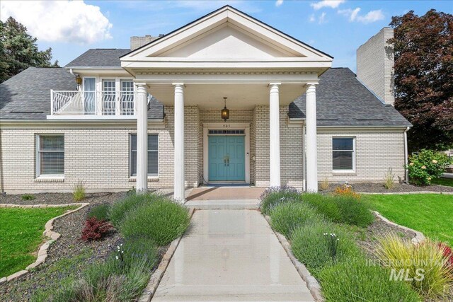 905 S Canyon St, Nampa, ID 83686 - view of front of home featuring brick siding, covered porch, a balcony, and a chimney