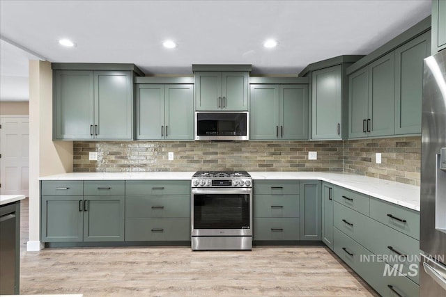 905 S Canyon St, Nampa, ID 83686 - kitchen with appliances with stainless steel finishes, green cabinets, light wood-style floors, tasteful backsplash, and recessed lighting