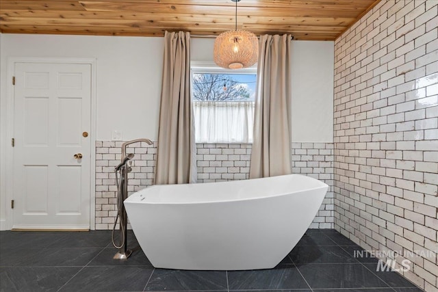 905 S Canyon St, Nampa, ID 83686 - bathroom featuring wood ceiling, tile walls, tile patterned floors, a freestanding tub, and a wainscoted wall