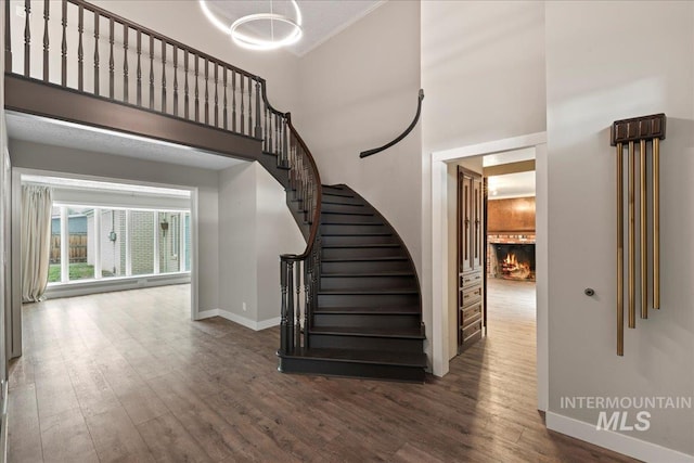 905 S Canyon St, Nampa, ID 83686 - stairs featuring wood finished floors, baseboards, a warm lit fireplace, a high ceiling, and a chandelier