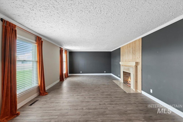 905 S Canyon St, Nampa, ID 83686 - unfurnished living room with a textured ceiling, crown molding, plenty of natural light, a fireplace, and wood finished floors