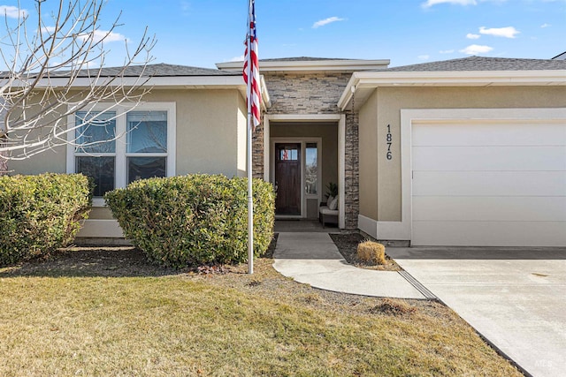 entrance to property featuring stone siding, a lawn, an attached garage, and stucco siding