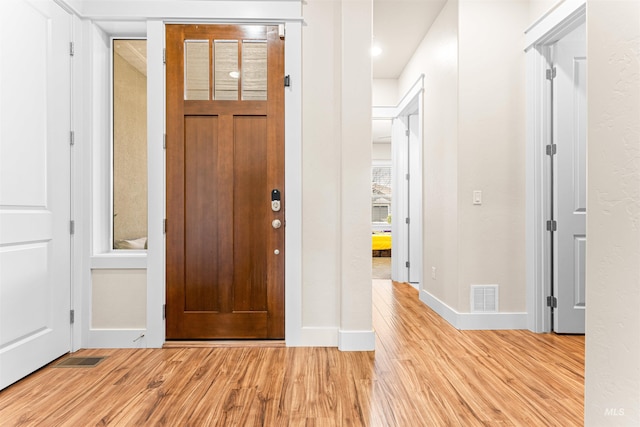 foyer featuring light wood-style floors, visible vents, and baseboards