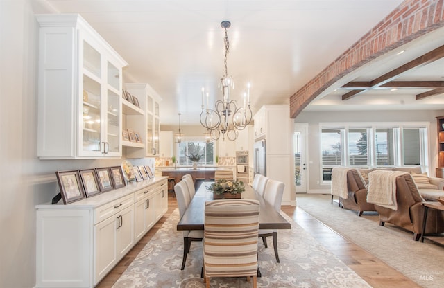 14050 Hidalgo Ranch Pl, Nampa, ID 83651 - dining area featuring arched walkways, beamed ceiling, a notable chandelier, and wood finished floors