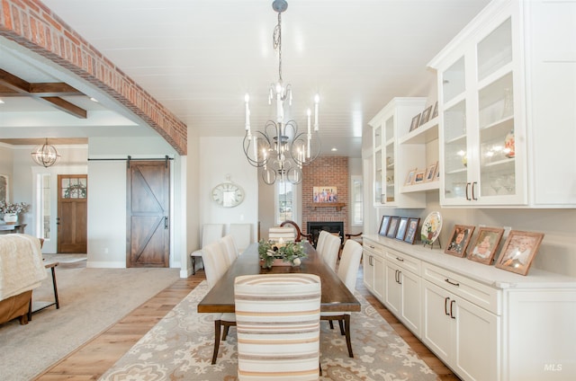 14050 Hidalgo Ranch Pl, Nampa, ID 83651 - dining area with a brick fireplace, light wood-type flooring, a barn door, baseboards, and an inviting chandelier