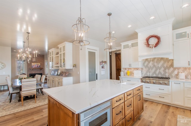 14050 Hidalgo Ranch Pl, Nampa, ID 83651 - kitchen featuring a sink, light wood-style floors, pendant lighting, and a notable chandelier