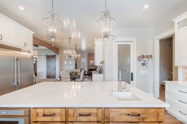 14050 Hidalgo Ranch Pl, Nampa, ID 83651 - kitchen featuring light stone counters, a barn door, a sink, and white cabinets