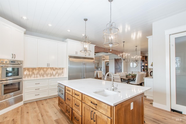 14050 Hidalgo Ranch Pl, Nampa, ID 83651 - kitchen with light wood-type flooring, a sink, built in appliances, and an island with sink