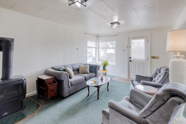 living room featuring crown molding, a wood stove, and baseboards