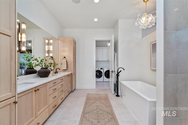938 S Waning Ln, Eagle, ID 83616 - bathroom featuring washer and dryer, double vanity, a chandelier, a soaking tub, and tile patterned flooring