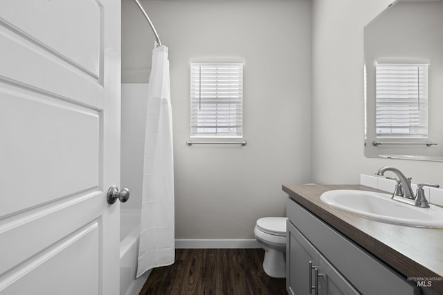 full bathroom with baseboards, toilet, shower / tub combo with curtain, wood finished floors, and vanity