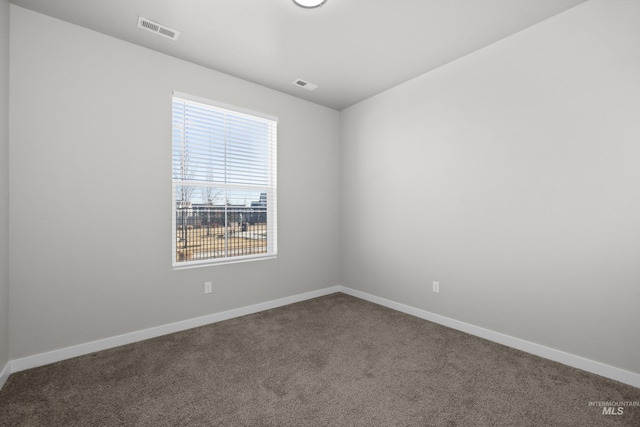 spare room with carpet floors, visible vents, and baseboards