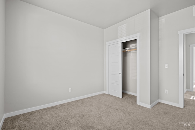 unfurnished bedroom featuring a closet, baseboards, and carpet flooring