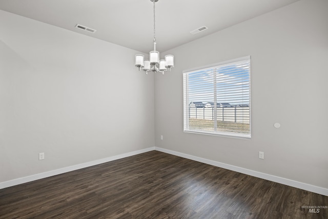 empty room featuring visible vents, baseboards, dark wood-type flooring, and a notable chandelier