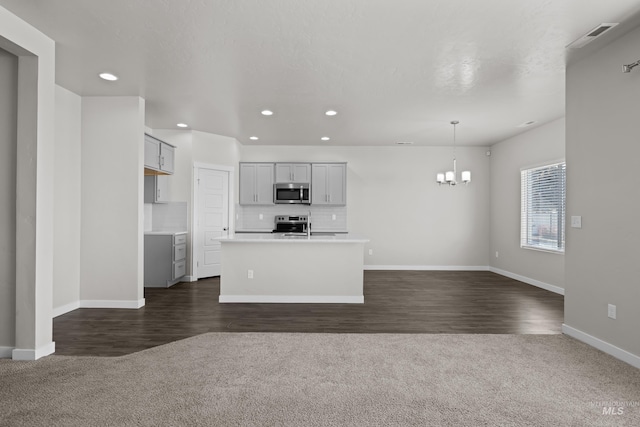 kitchen with stainless steel appliances, gray cabinets, backsplash, open floor plan, and a chandelier