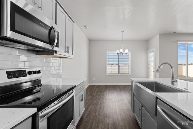 kitchen featuring tasteful backsplash, dark wood-style flooring, stainless steel appliances, pendant lighting, and a sink