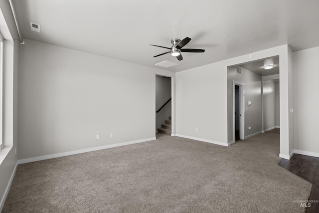 empty room with visible vents, ceiling fan, stairway, and baseboards