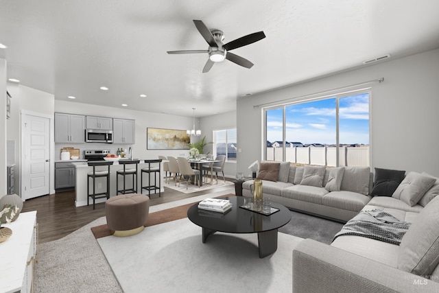 living area featuring recessed lighting, dark wood-style flooring, visible vents, and ceiling fan with notable chandelier