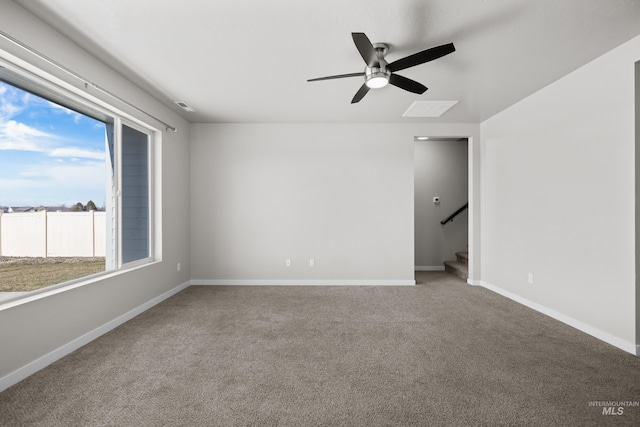 unfurnished room featuring carpet floors, ceiling fan, stairway, and baseboards