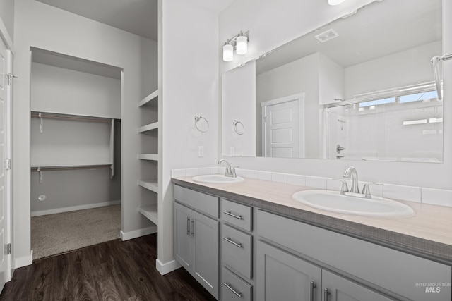 full bath featuring visible vents, a sink, a shower stall, and wood finished floors