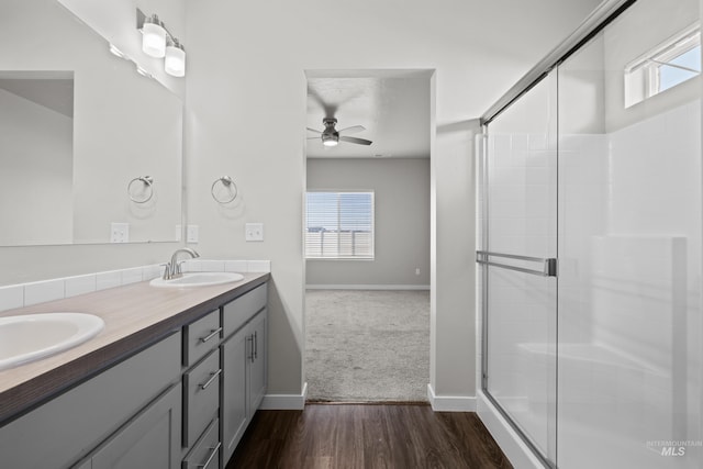 bathroom with double vanity, wood finished floors, a stall shower, and a sink