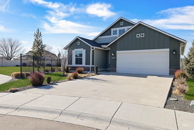 view of front of house featuring driveway, stone siding, fence, a front lawn, and board and batten siding