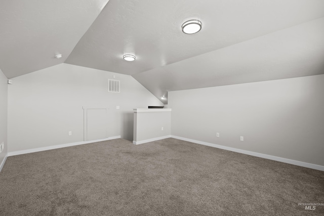 additional living space featuring carpet flooring, visible vents, vaulted ceiling, and baseboards