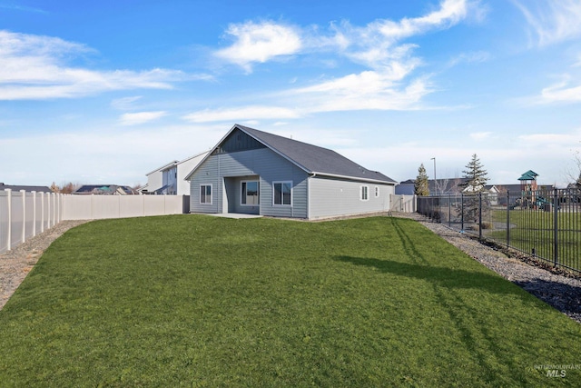 rear view of house featuring a fenced backyard and a lawn