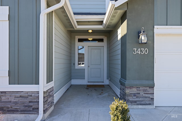 property entrance featuring stone siding and an attached garage