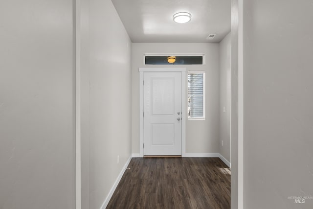 doorway with dark wood-style floors, visible vents, and baseboards