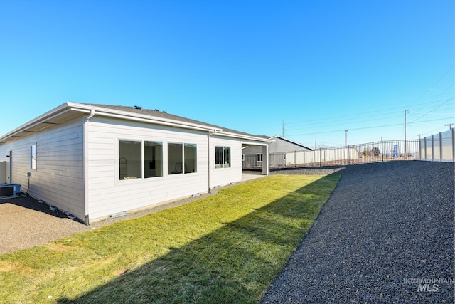 back of house with central AC unit and a yard