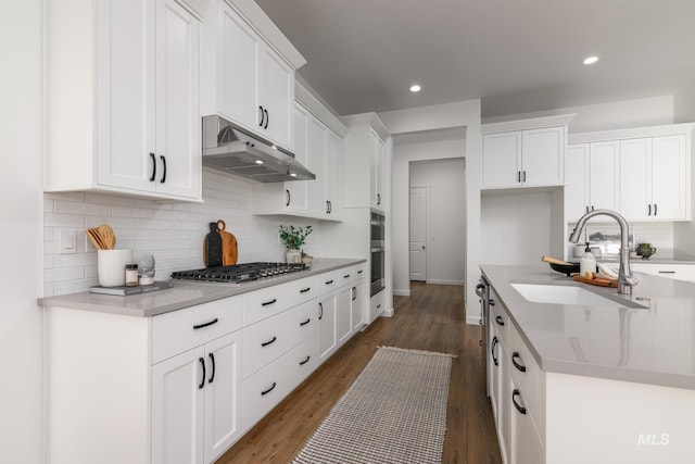 kitchen featuring dark wood-type flooring, sink, white cabinetry, tasteful backsplash, and appliances with stainless steel finishes