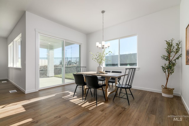 dining room with plenty of natural light, dark hardwood / wood-style floors, and an inviting chandelier