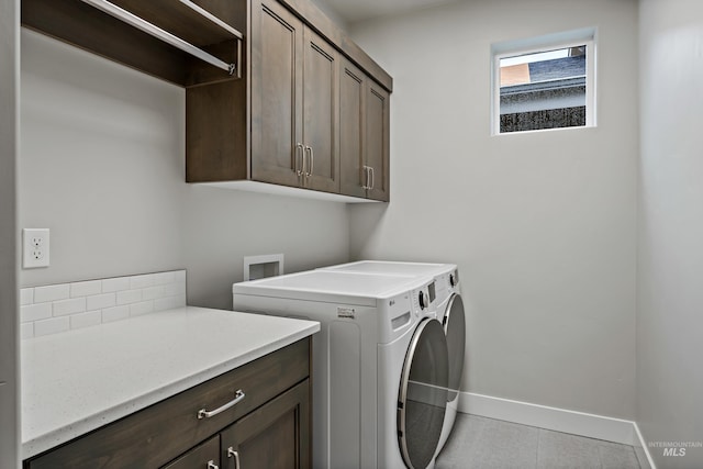 laundry room with washing machine and dryer, light tile patterned flooring, and cabinets