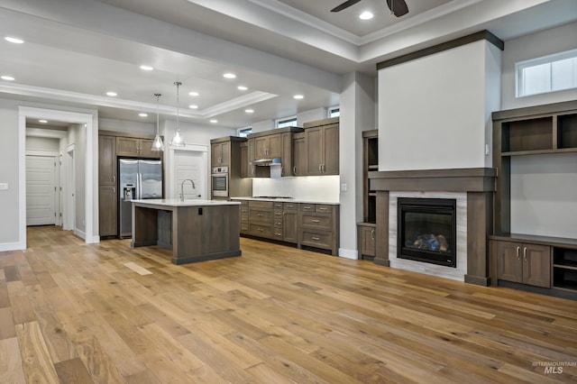 kitchen featuring appliances with stainless steel finishes, a breakfast bar, a raised ceiling, pendant lighting, and a center island with sink