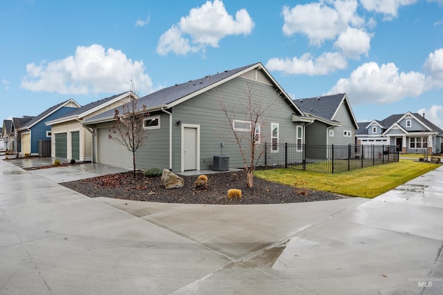 exterior space featuring central AC unit, a garage, and a yard