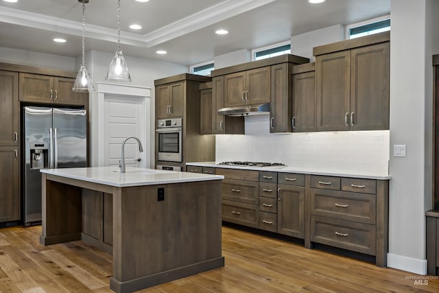 kitchen featuring hanging light fixtures, dark brown cabinetry, an island with sink, and appliances with stainless steel finishes