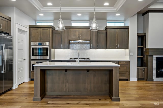 kitchen featuring pendant lighting, dark brown cabinets, a center island with sink, and appliances with stainless steel finishes