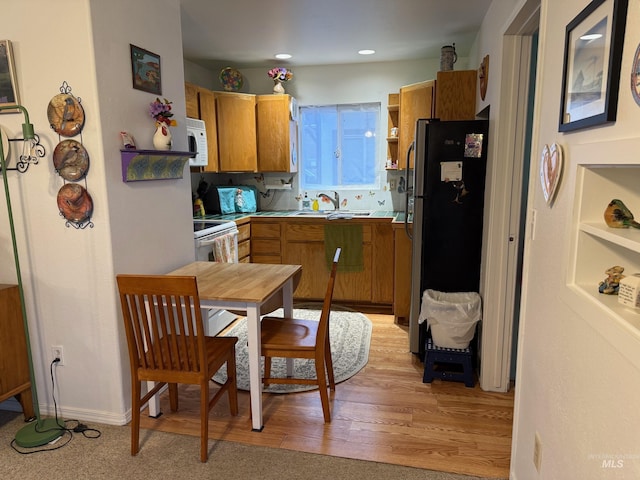 kitchen with sink, white appliances, and light hardwood / wood-style flooring