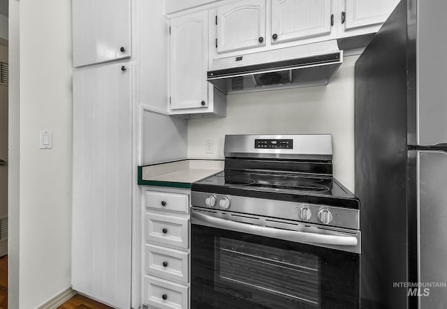 kitchen featuring stainless steel appliances, under cabinet range hood, white cabinetry, light countertops, and wood finished floors