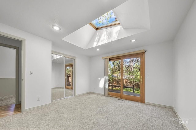 unfurnished bedroom featuring a skylight, carpet flooring, access to exterior, recessed lighting, and baseboards