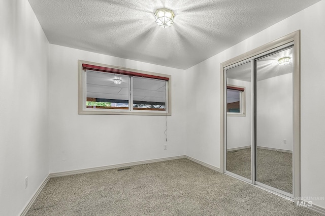 unfurnished bedroom featuring carpet flooring, a textured ceiling, baseboards, and a closet