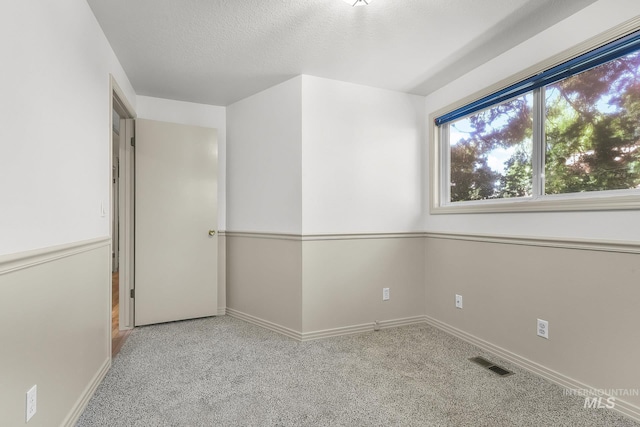 unfurnished room with carpet flooring, baseboards, and a textured ceiling