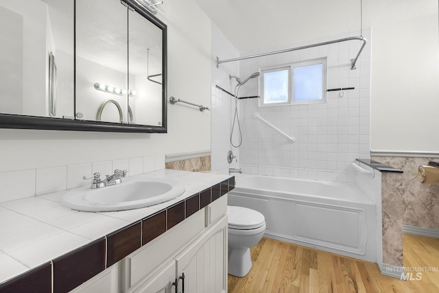 full bath featuring shower / washtub combination, wood finished floors, toilet, a wainscoted wall, and vanity