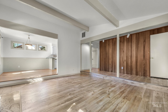 unfurnished living room featuring hardwood / wood-style flooring, wooden walls, and a wainscoted wall