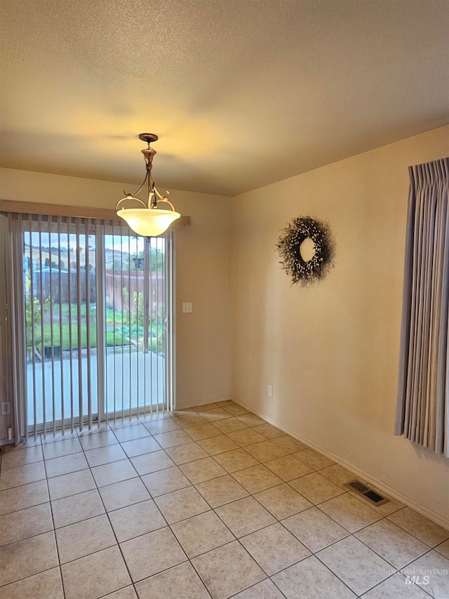 unfurnished room featuring light tile patterned floors and a textured ceiling